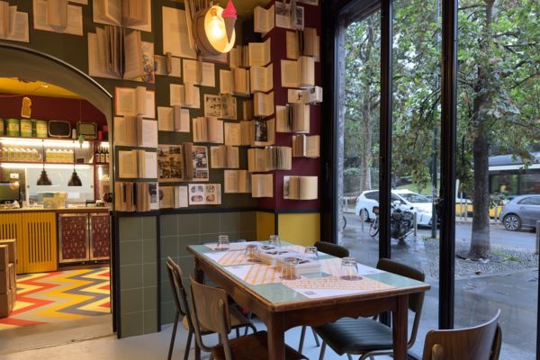 Interno di Fradiavolo Milano: tavolo apparecchiato, pareti con libri aperti. Design unico, nuova apertura.