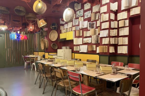 Interni di Fradiavolo Modena: tavoli apparecchiati, decorazioni con libri e ceste. Nuova pizzeria a Modena.