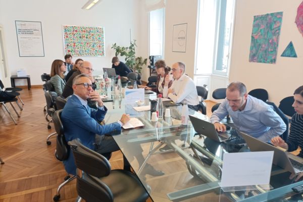 Riunione Osservatorio Food Court: analisi mercato. Persone sedute attorno a un tavolo con laptop, discutendo nuove strategie.