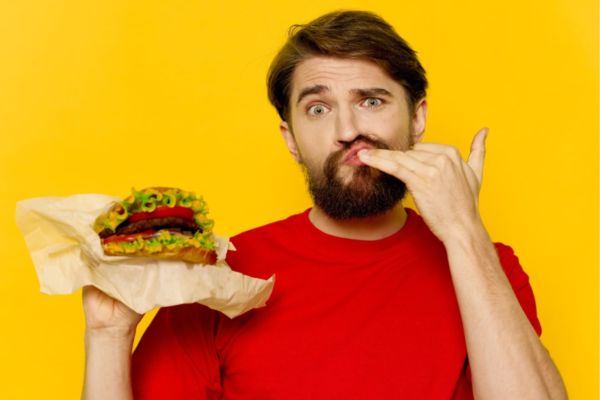 Uomo assaggia hamburger plant-based. Ristorazione vegana, futuro del cibo?