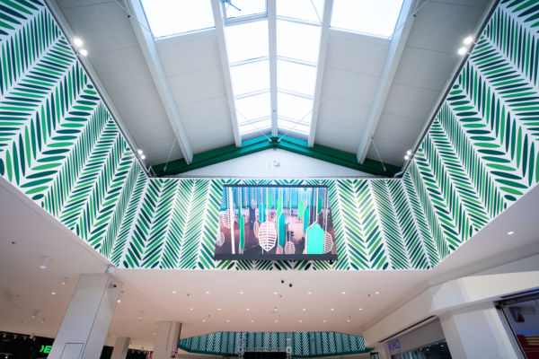 Interno del Centro Commerciale Portogrande dopo il restyling: pareti con decorazioni verdi e lucernario.