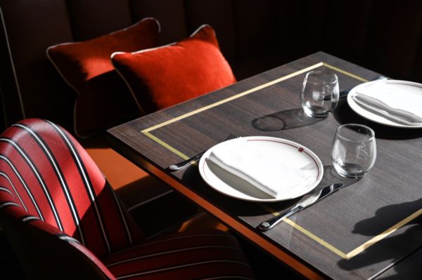 Interni Crazy Pizza: tavolo apparecchiato, sedie a righe rosse, cuscini. Design elegante, atmosfera accogliente.