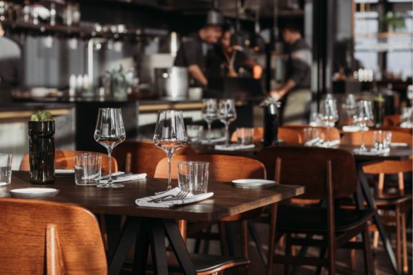 Tavoli apparecchiati in ristorante. Ristorazione di lusso, calici, posate e sedie in legno.